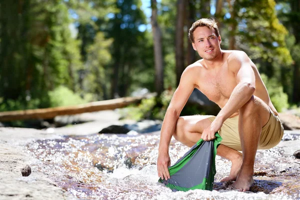 Hiker man washing clothes in river — Stock Photo, Image