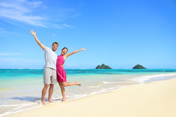 Carefree couple arms raised on the beach — Stock Photo, Image