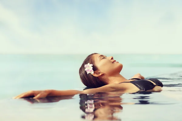 Mulher relaxante na piscina infinita — Fotografia de Stock