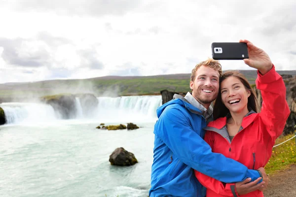 Couple taking smartphone picture of waterfall — Stock Photo, Image