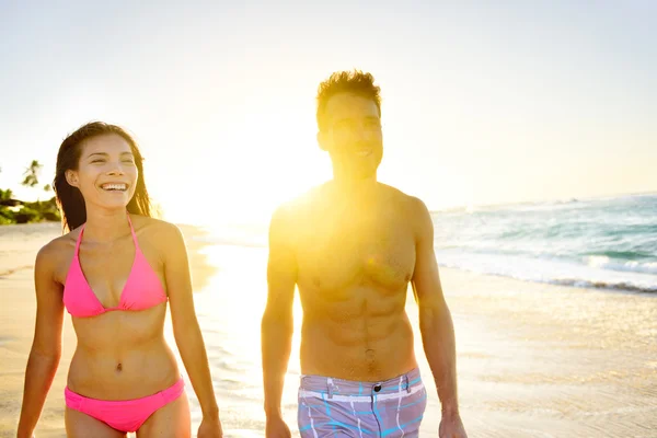 Paar spaziert bei Sonnenuntergang am Strand — Stockfoto