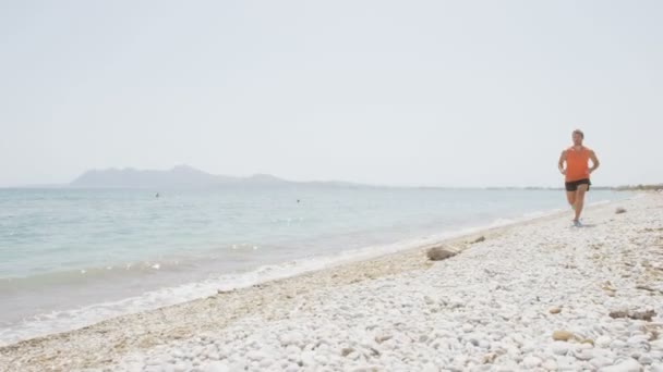 Hombre corriendo en la playa — Vídeo de stock