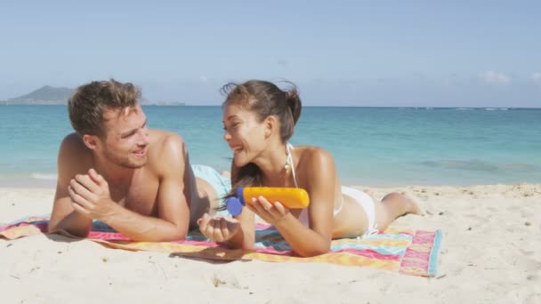 Mulher ajudando o homem com protetor solar na praia — Vídeo de Stock