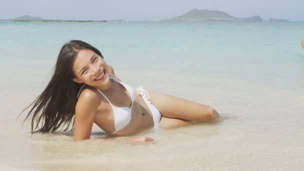 Пляжная девушка в бикини лежит на песке — стоковое видео