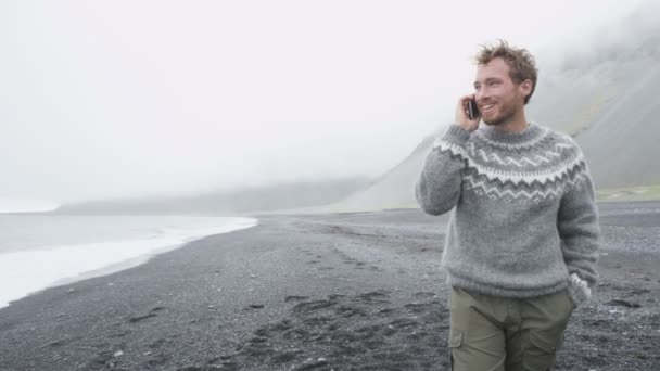Мужчина разговаривает по телефону на пляже — стоковое видео