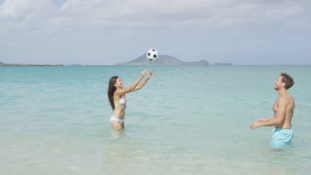 Pareja en la playa jugando pelota en el agua — Vídeo de stock