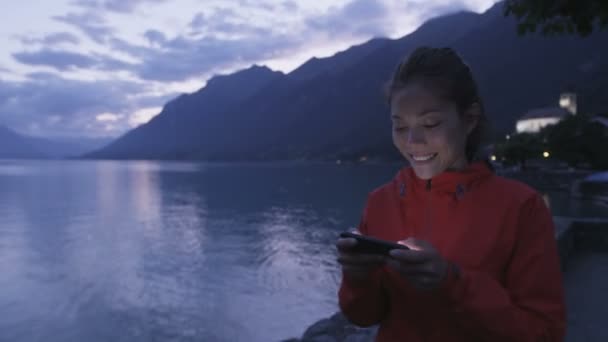 Mensagens de texto menina usando telefone inteligente por lago — Vídeo de Stock