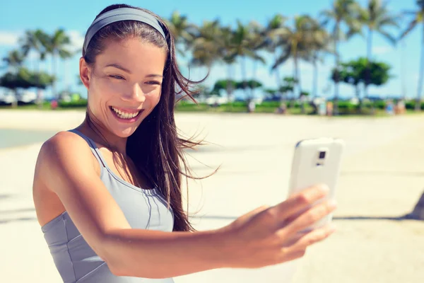 Woman on palm beach with smartphone — 图库照片