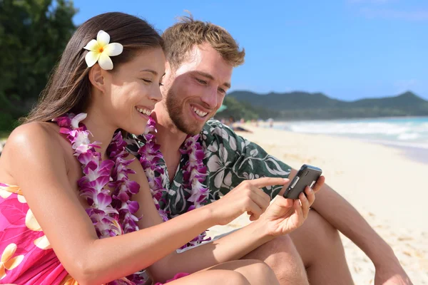 Pareja en la playa con smartphone en Hawaii —  Fotos de Stock
