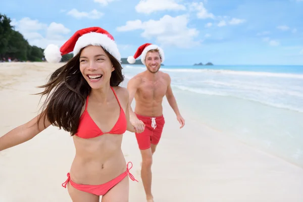 Christmas couple running on beach — Zdjęcie stockowe