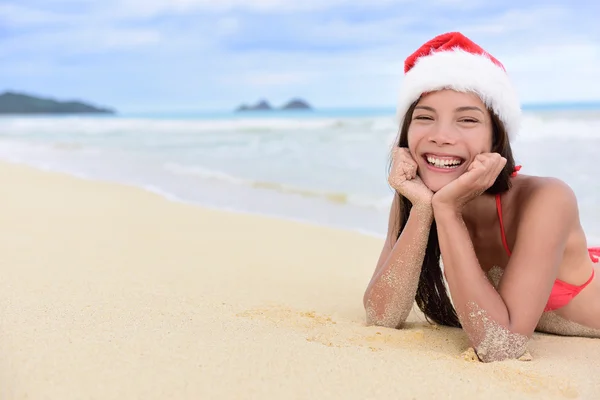 Girl in Santa hat lying on beach — стокове фото