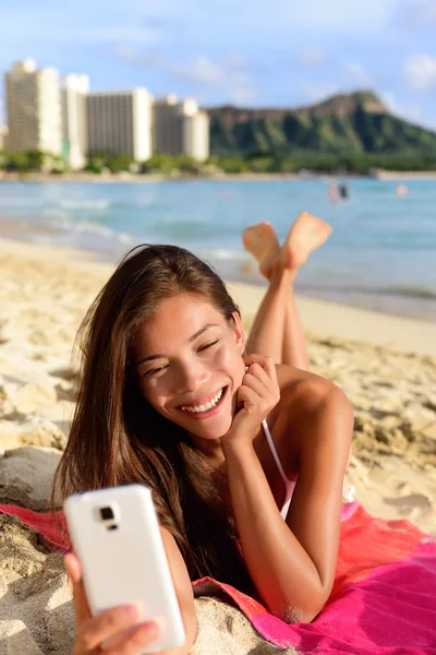 Mujer usando aplicación de teléfono inteligente en la playa — Foto de Stock