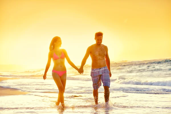 Couple in swimwear walking at beach — ストック写真