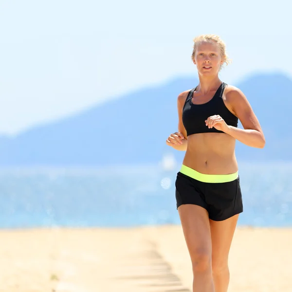 Donna in abbigliamento sportivo in esecuzione in spiaggia — Foto Stock