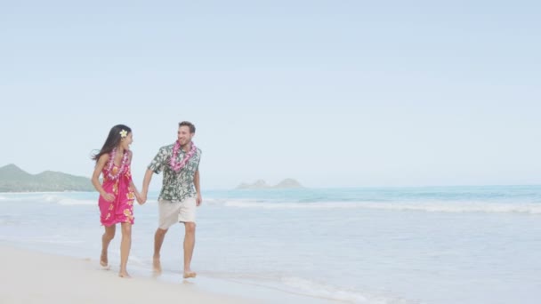 Pareja en Aloha ropa corriendo en la playa — Vídeo de stock