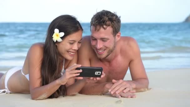Strandpaar mit Smartphone hat Spaß — Stockvideo