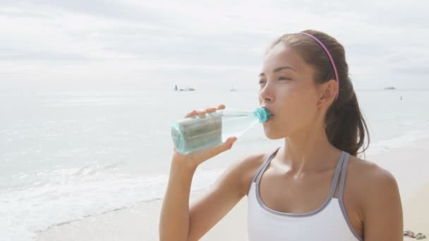 Mujer bebiendo agua en la playa — Vídeos de Stock