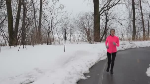 Kvinnan jogging på vägen på vintern — Stockvideo