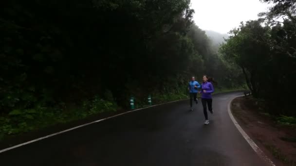 Жінка і чоловік біжать по дорозі — стокове відео