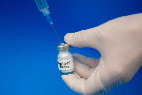 青い背景にCovid 19ワクチンの最初の投与量で満たされます — ストック写真