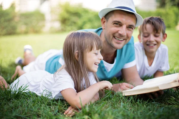 Vater Liest Seinen Kindern Ein Buch Vor Während Sie Draußen — Stockfoto