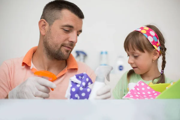 快乐的父亲和他的小女儿在家里一起打扫桌子 免版税图库图片