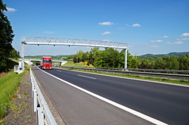 Ormanlık bir manzara bir karayolu üzerinde geçis kapı doğru gelen kırmızı kamyon
