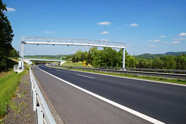 Portail de péage électronique au-dessus d'une autoroute vide dans un paysage boisé — Photo