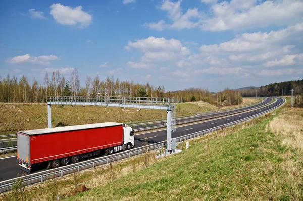 Camión pasando puertas de peaje electrónicas en la autopista de asfalto en el paisaje — Foto de Stock