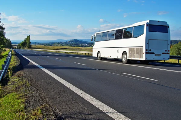 Weißer Bus fährt auf leerer Straße in ländlicher Landschaft — Stockfoto