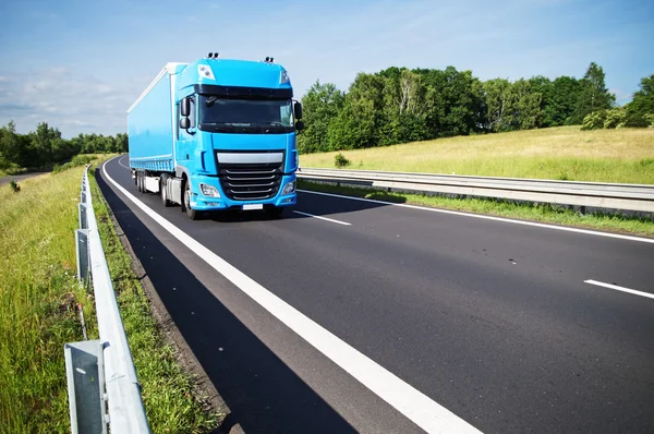 Blå lastbil på asfalt motortrafikled på landsbygden — Stockfoto