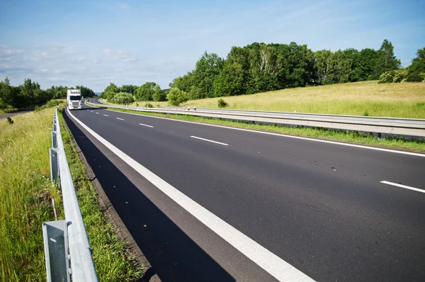 Empty asphalt expressway with white truck arriving from afar in the countryside — Stock Photo, Image