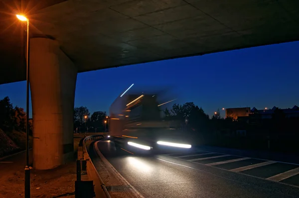 Speeding motion blur truck entering under the bridge at night — Stock Photo, Image