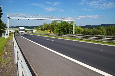 Ormanlık kırsal otoyol geçis gates. Beyaz kamyon uzaktan geçiş ücreti kapıda geldi. Beton köprü ve arka planda ormanlık dağlar.