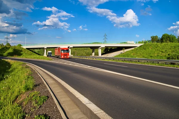 Most přes prázdná silnice na venkově, pod mostem prochází dva nákladní automobily — Stock fotografie