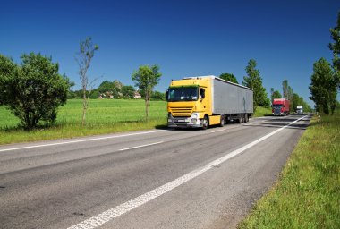 Road, kırsal peyzaj ağaçları ile kaplı üç geçen kamyon renkli.