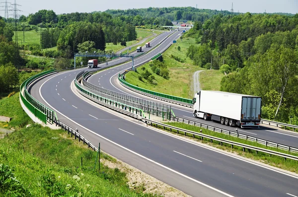 La carretera entre bosques, en medio de las puertas de peaje electrónico de la carretera, camiones en movimiento —  Fotos de Stock