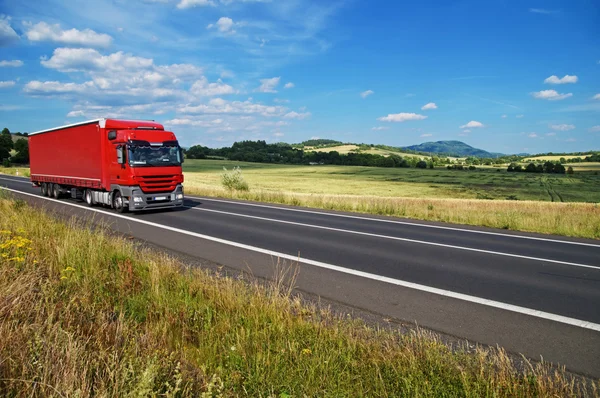 Ländliche Landschaft mit Straße, auf der Sie einen roten LKW fahren — Stockfoto