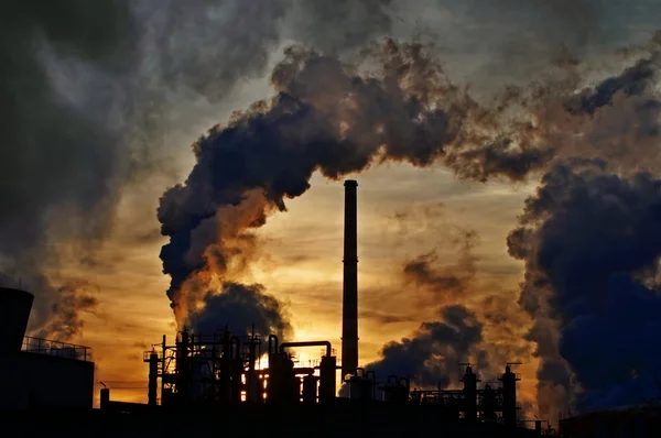 Schoorstenen en donkere rook over chemische fabriek bij zonsondergang Rechtenvrije Stockafbeeldingen