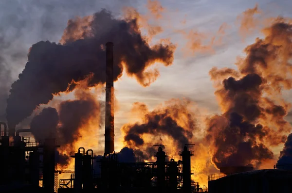 Schoorstenen en donkere rook over chemische fabriek bij zonsondergang Rechtenvrije Stockfoto's