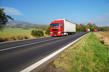 Kırsal kesimde yol üzerinde üç kırmızı kamyon