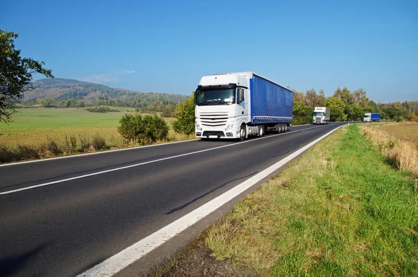 Drei weiße Lastwagen auf dem Land unterwegs — Stockfoto