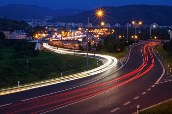 La ciudad con alumbrado público en el valle por la noche, los faros del camino de la luz de los coches — Foto de Stock