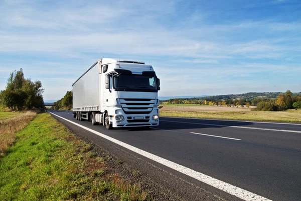 Camion blanc se déplace sur la route asphaltée dans la campagne, couleurs de début d'automne — Photo