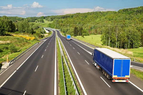 Blue trucks driving down the highway in the countryside. — Stock Photo, Image