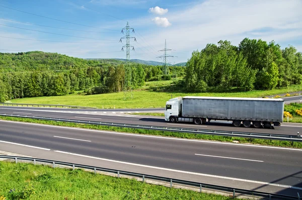 Ett land landskap med motorvägen och åka lastbil. Pyloner av elektriska kraftledningar. — Stockfoto