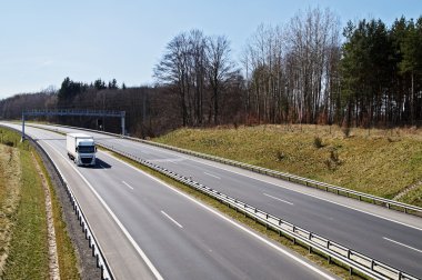 Otoyol erken Bahar ormanda çevresinde. Beyaz kamyonetin altına geçis kapıları.