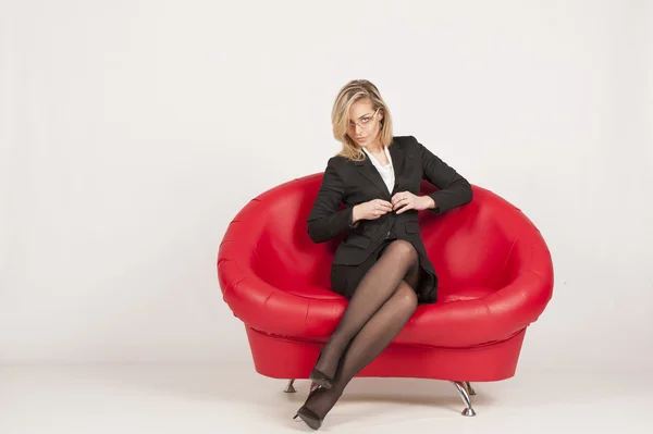 Woman undresses on a red couch — Stock Photo, Image