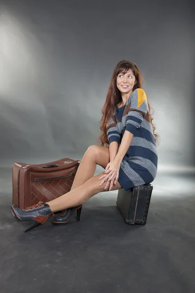 A brunette woman posing on a suitcase — Stock Photo, Image
