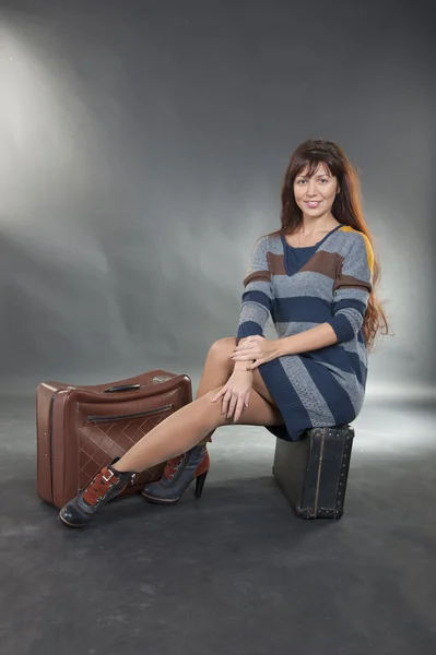 Brunette meisje die zich voordeed op een koffer — Stockfoto